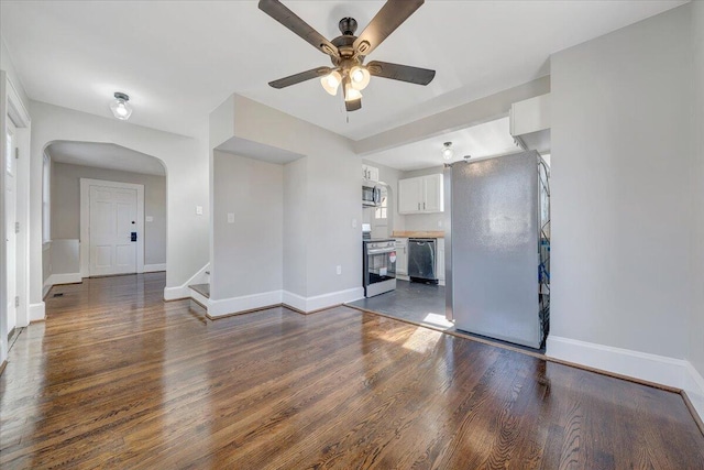 unfurnished living room featuring stairway, a ceiling fan, baseboards, and dark wood-style flooring