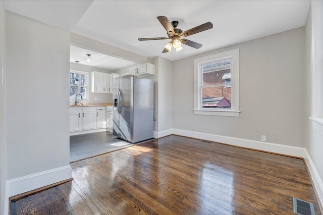 interior space featuring baseboards, visible vents, dark wood-style flooring, and a sink