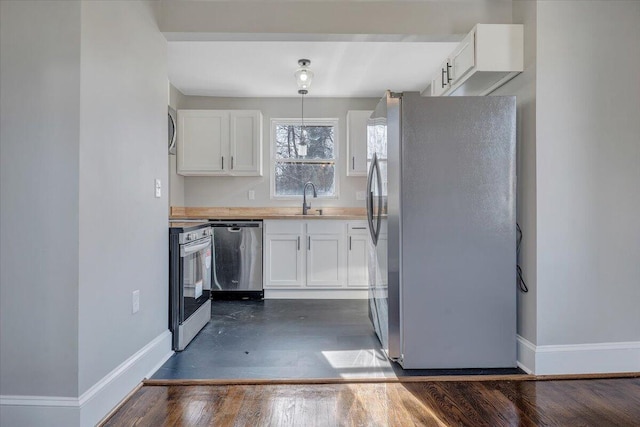 kitchen with white cabinets, stainless steel appliances, baseboards, and a sink