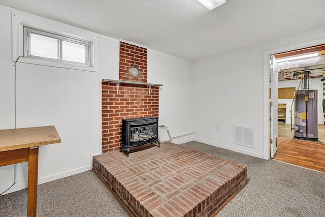 living area with water heater, visible vents, carpet flooring, and baseboards