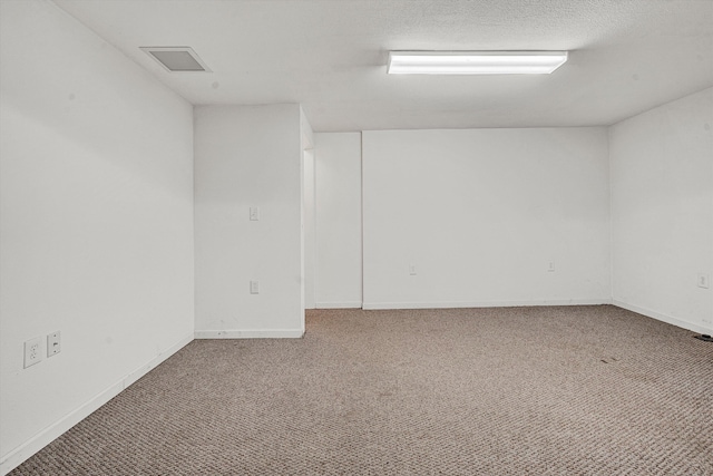 unfurnished room with visible vents, baseboards, carpet, and a textured ceiling