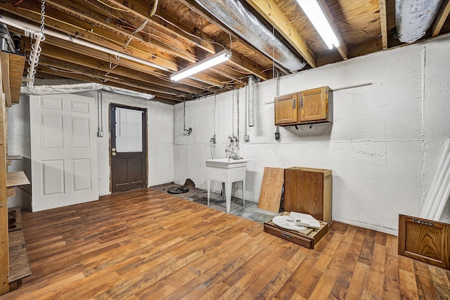 unfinished below grade area with hardwood / wood-style flooring and a sink