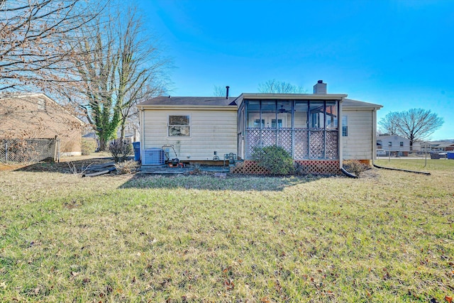 back of house with central air condition unit, a lawn, a chimney, and a sunroom