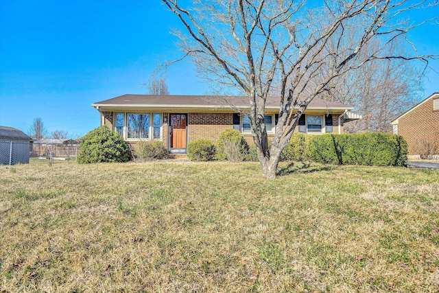 ranch-style house with a front yard, fence, and brick siding