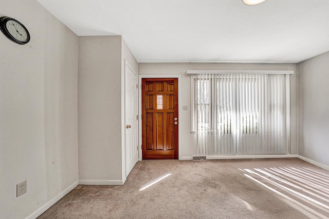 carpeted entrance foyer featuring visible vents and baseboards