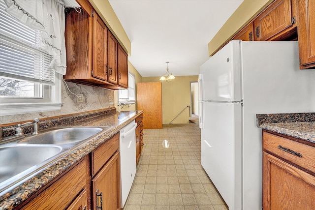 kitchen with a notable chandelier, brown cabinets, white appliances, and a sink