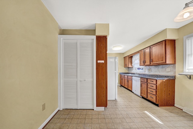 kitchen with visible vents, dark countertops, white appliances, brown cabinetry, and baseboards