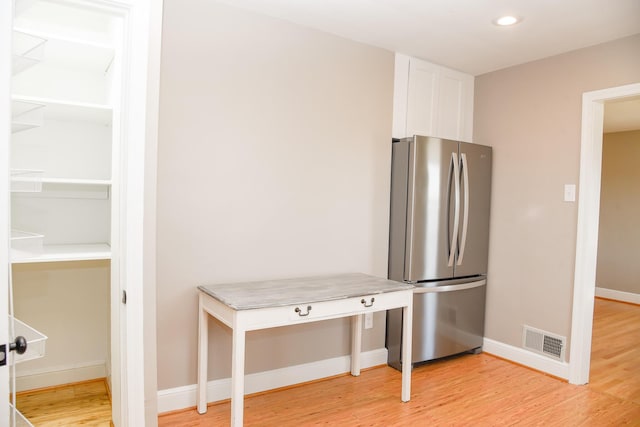 kitchen featuring light wood-type flooring, visible vents, white cabinetry, and freestanding refrigerator