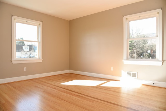 unfurnished room with visible vents, baseboards, and wood finished floors