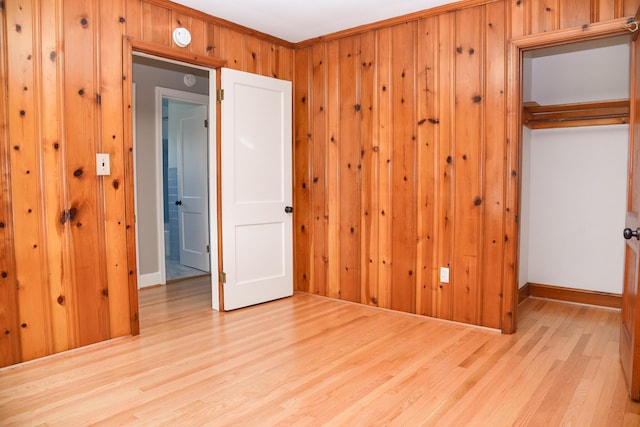 unfurnished bedroom featuring a closet, wood finished floors, and wood walls