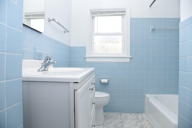 full bathroom with vanity, wainscoting, tile walls, toilet, and marble finish floor