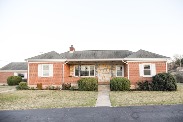 view of front of home with stone siding, a front lawn, roof with shingles, and a chimney