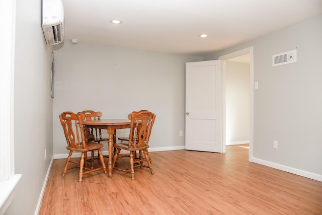 dining space with visible vents, a wall mounted AC, recessed lighting, light wood finished floors, and baseboards