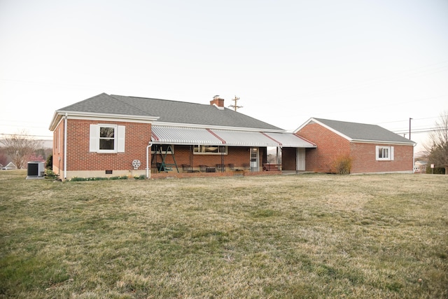 back of house featuring crawl space, cooling unit, brick siding, and a yard