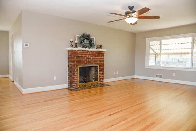 unfurnished living room with light wood-type flooring, baseboards, and a brick fireplace