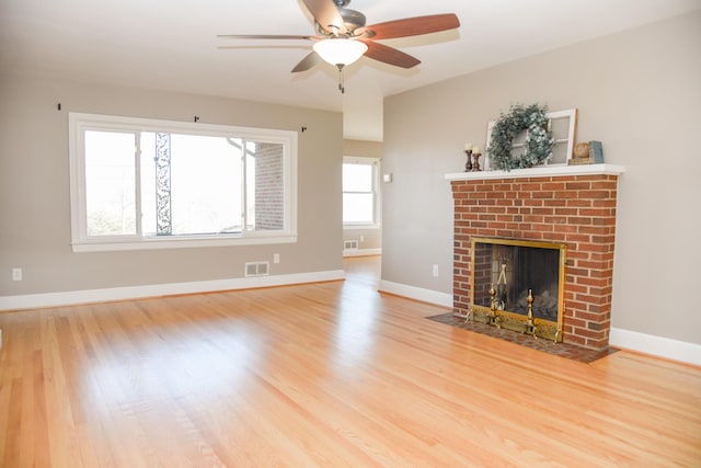 unfurnished living room featuring wood finished floors, a fireplace, visible vents, and baseboards