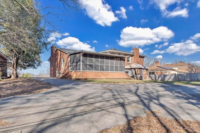 exterior space featuring a chimney, a sunroom, and fence