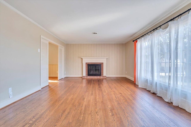 unfurnished living room featuring baseboards, a brick fireplace, wood finished floors, and ornamental molding