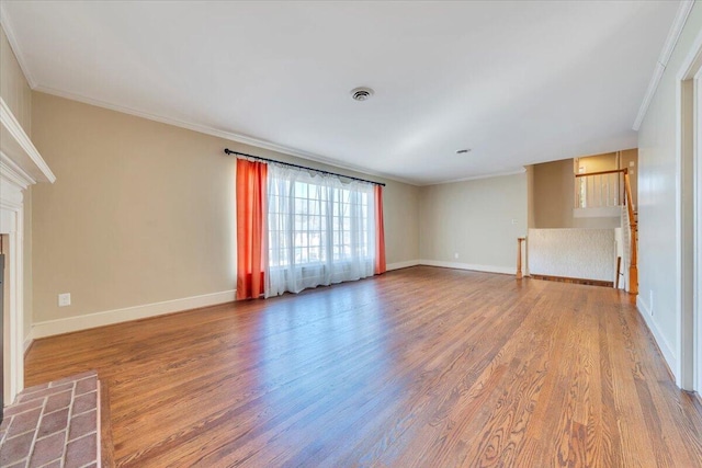 unfurnished living room featuring visible vents, baseboards, wood finished floors, and crown molding