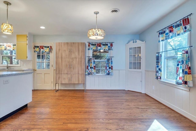 unfurnished dining area featuring visible vents, a sink, recessed lighting, light wood-style floors, and wainscoting