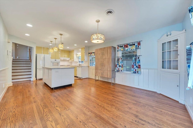 kitchen featuring visible vents, white appliances, a kitchen island, and wood finished floors