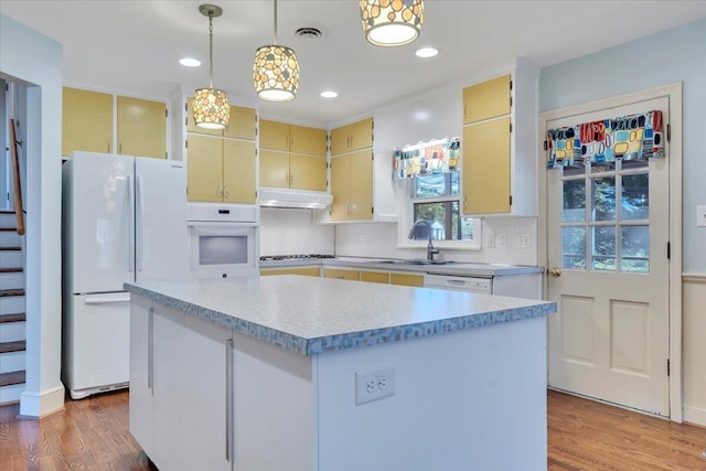 kitchen featuring white appliances, wood finished floors, visible vents, a sink, and cream cabinetry