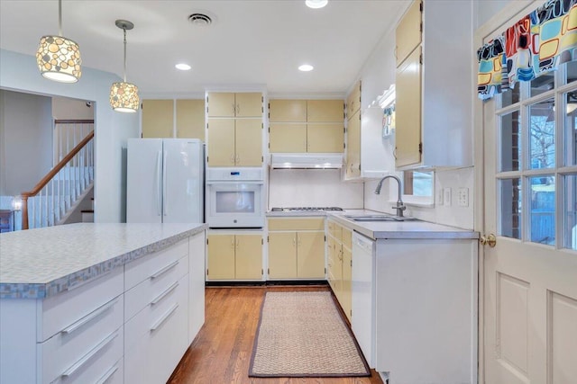 kitchen featuring white appliances, visible vents, a sink, under cabinet range hood, and cream cabinets