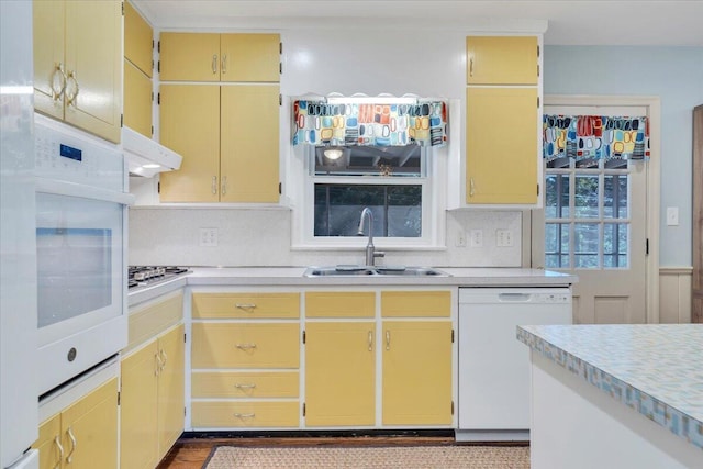 kitchen featuring under cabinet range hood, white appliances, light countertops, and a sink