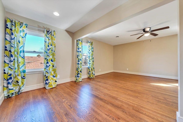 unfurnished room with a wealth of natural light, ceiling fan, baseboards, and wood finished floors