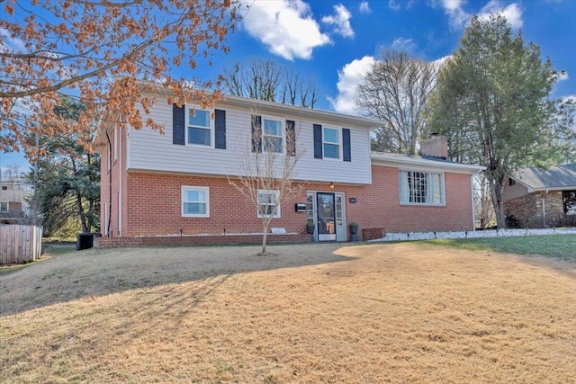 view of front of house with brick siding, a chimney, and a front yard