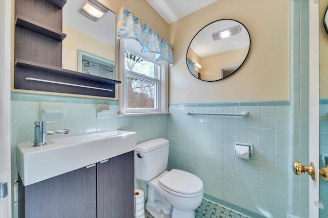 bathroom featuring a wainscoted wall, toilet, tile walls, and vanity