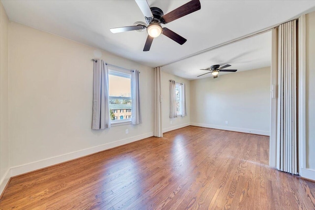 spare room with a ceiling fan, wood finished floors, and baseboards