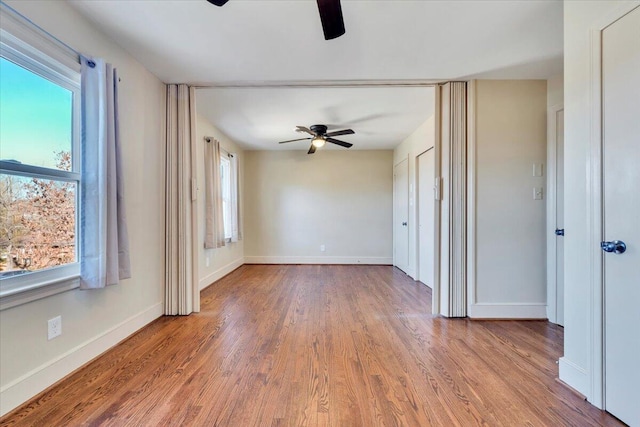 unfurnished room with wood finished floors, a healthy amount of sunlight, and ceiling fan