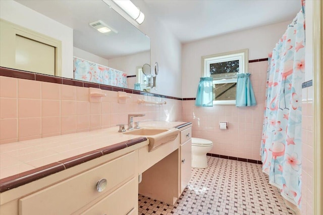 bathroom featuring visible vents, curtained shower, toilet, vanity, and tile walls