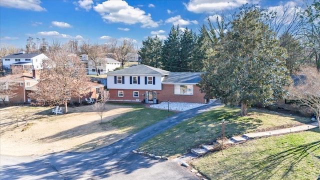 tri-level home with brick siding and a front yard