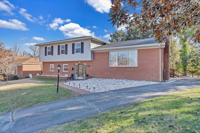 tri-level home with brick siding and a front lawn