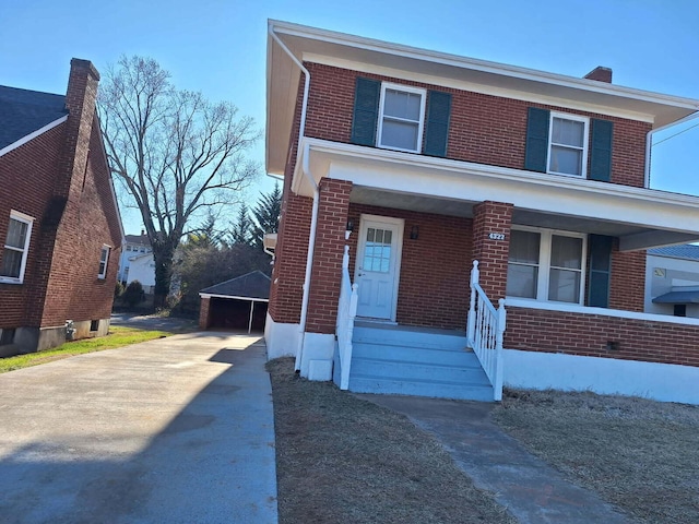 view of front of house featuring brick siding, a porch, and a detached garage