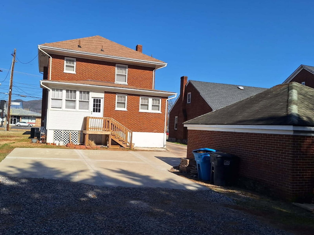 back of house with brick siding and a chimney