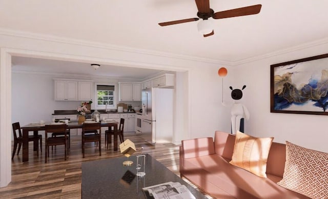 living room featuring dark wood finished floors, crown molding, and a ceiling fan