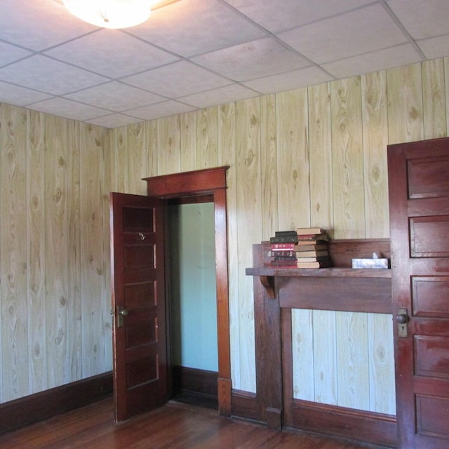 interior space with a paneled ceiling, baseboards, and wood finished floors