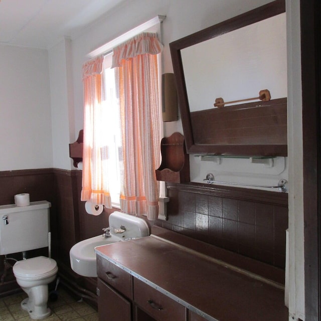 bathroom featuring a wainscoted wall, toilet, a bidet, and a sink