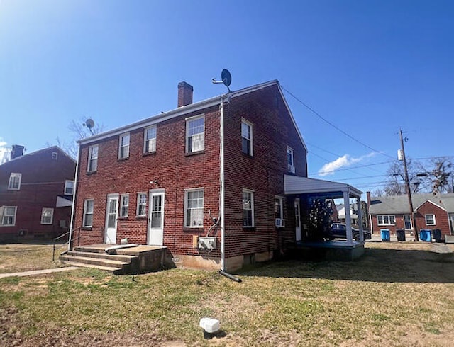 back of property with a yard, brick siding, and a chimney