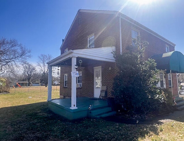 view of side of property featuring a porch, a yard, and brick siding