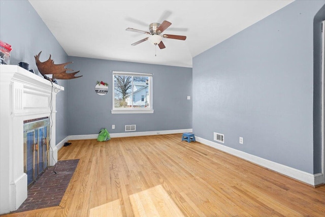 unfurnished living room with visible vents, baseboards, a fireplace with flush hearth, and wood finished floors