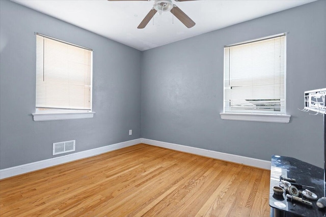 unfurnished room featuring wood finished floors, baseboards, visible vents, and ceiling fan