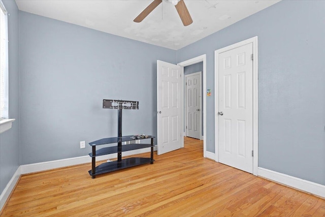 interior space featuring light wood-style flooring, a ceiling fan, and baseboards