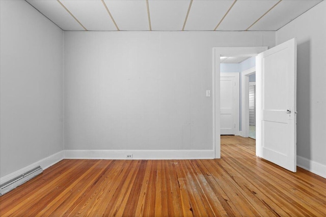 spare room featuring a baseboard heating unit, baseboards, and light wood-style floors