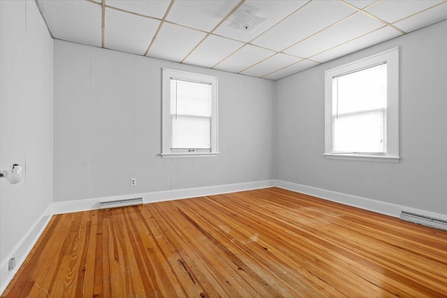 unfurnished room with a drop ceiling, visible vents, a healthy amount of sunlight, and hardwood / wood-style floors