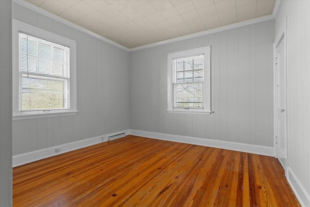 spare room with a wealth of natural light, ornamental molding, and hardwood / wood-style flooring