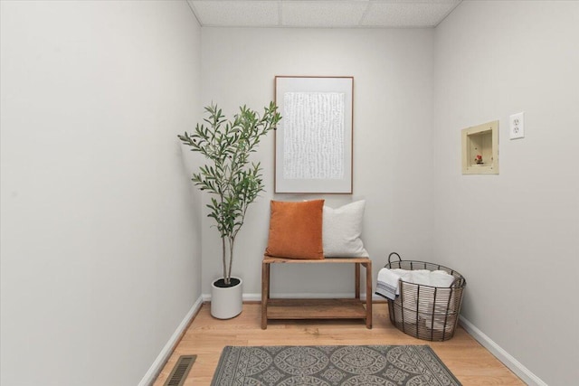 living area featuring visible vents, light wood-style flooring, a paneled ceiling, and baseboards